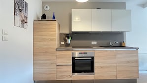 A modern kitchen with wooden cabinets, a built-in oven, and a stainless steel sink.