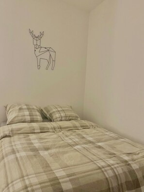 A bedroom with a bed, two pillows, and a wall decal of a deer.