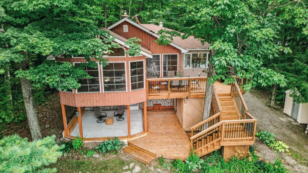 Una cabaña de madera con terraza, mobiliario exterior y una escalera.