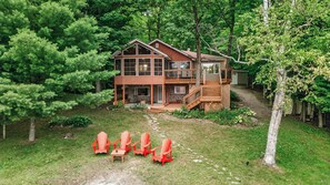 A two-story wooden cabin with a stone foundation, surrounded by dense forest. - Charming 3-bedroom cottage with AC in beautiful Georgian Bay (Georgian Bay)