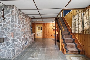 A hallway with a stone wall, a wooden staircase, and a tiled floor. - Charming 3-bedroom cottage with AC in beautiful Georgian Bay (Georgian Bay)