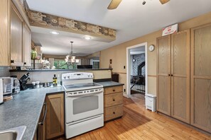 A kitchen with a stove, oven, and wooden cabinets. - Charming 3-bedroom cottage with AC in beautiful Georgian Bay (Georgian Bay)