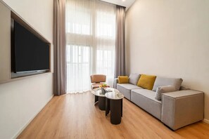 A modern living room with a sofa, a coffee table, and a TV mounted on the wall.