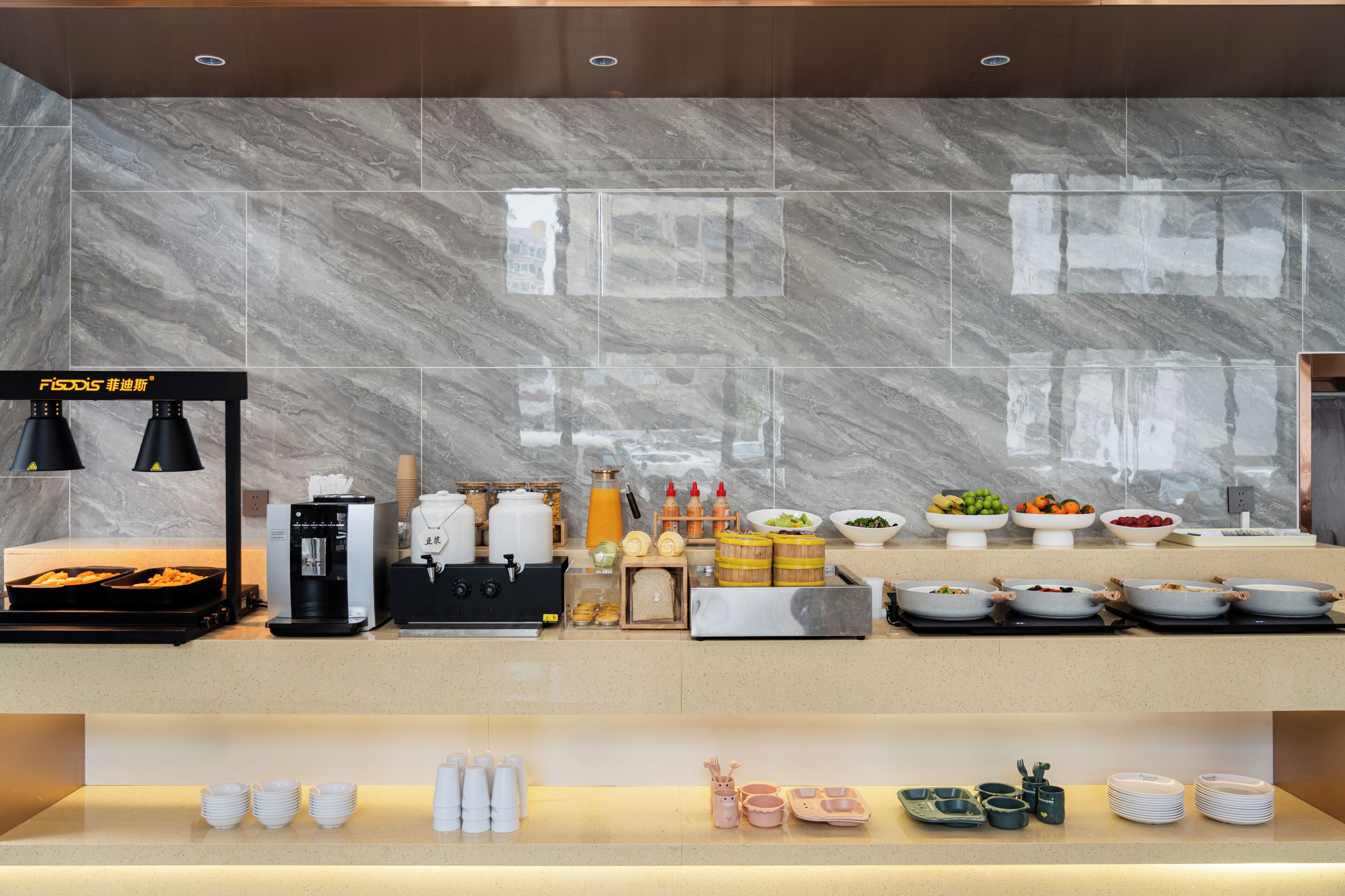 Zona de petit esmorzar d'hotel amb frontissa de marbre, una màquina de cafè i diversos dispensadors d'aliments i begudes.