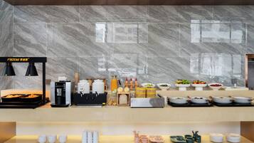 Zona de petit esmorzar d'hotel amb frontissa de marbre, una màquina de cafè i diversos dispensadors d'aliments i begudes.