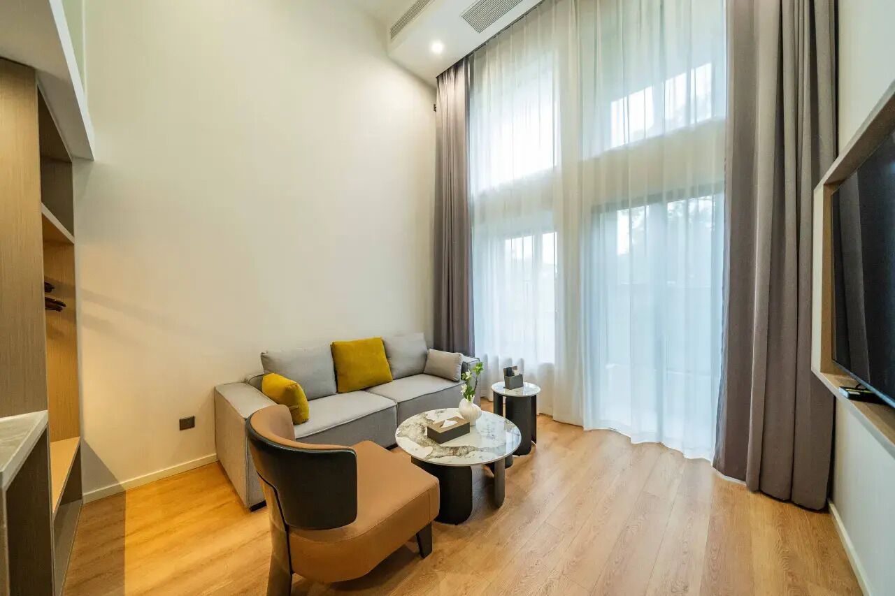 Una sala de estar moderna con un sofá, un sillón, una mesa de centro y un televisor de pantalla plana.