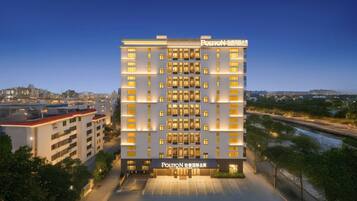 A multi-story hotel with a service apartment section, featuring a modern facade and illuminated windows.