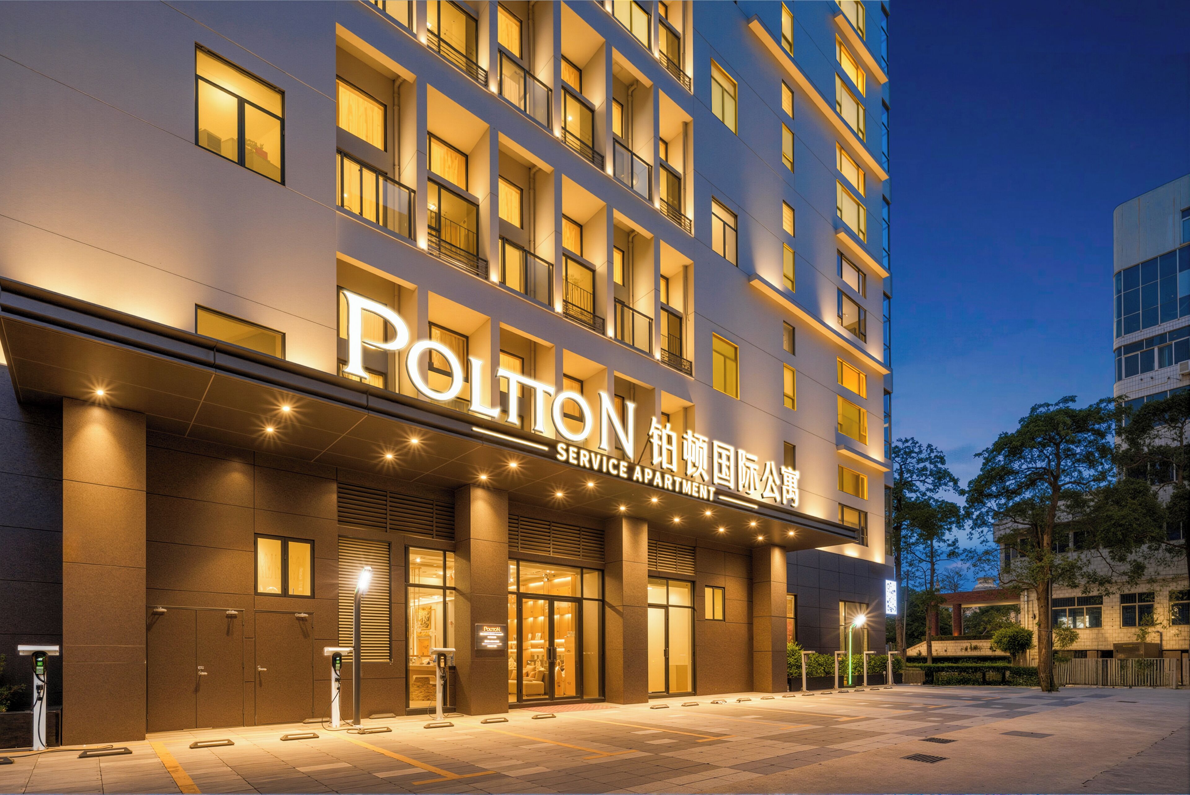 A multi-story hotel with a service apartment section, featuring a modern facade, illuminated signage, and a clean, well-lit entrance area.