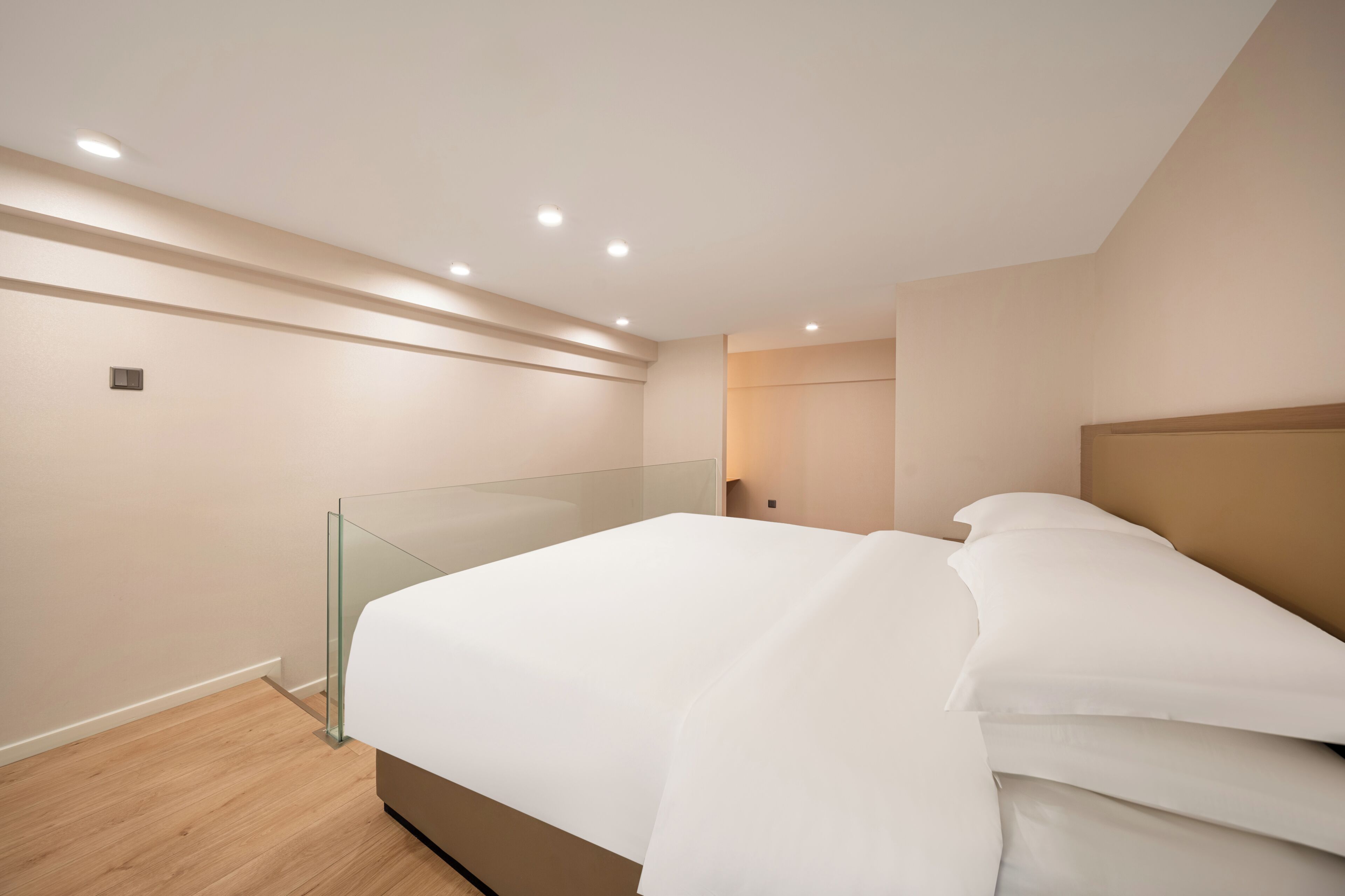 Ein modernes Schlafzimmer mit Glasbalkon, Holzboden und einem Bett mit weißer Bettwäsche.