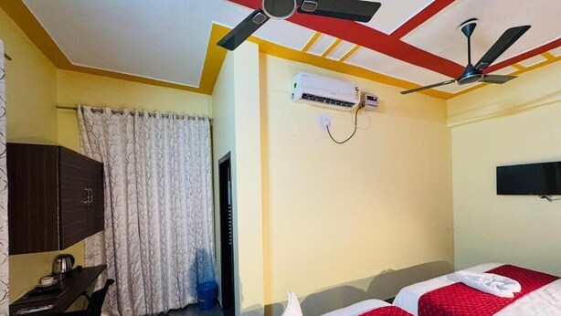 Habitación de hotel con dos camas, un escritorio, una silla, un equipo de aire acondicionado y ventiladores de techo.