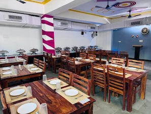 Comedor con varias mesas y sillas, unidades de aire acondicionado y un pilar decorativo.