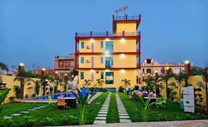 A multi-story building with a swimming pool, outdoor seating, and a well-maintained garden. - Elite Stay Hotel & Resort (Bawal)
