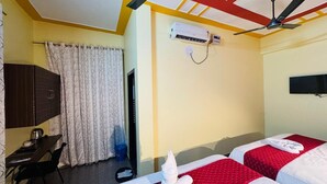 Et hotelværelse med to senge, et skrivebord, en stol, et fjernsyn og ventilatorer i loftet.