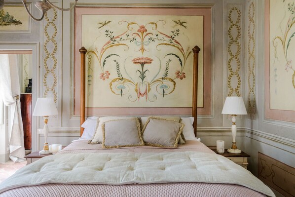 A bedroom with a large bed, two bedside tables, and a decorative wall mural. - Villa Maionchi: Timeless Tuscan Elegance & Luxury (Capannori)