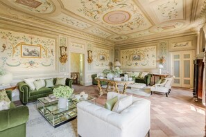 A luxurious room with ornate ceiling artwork, green and white furniture, and a marble floor. - Villa Maionchi: Timeless Tuscan Elegance & Luxury (Capannori)