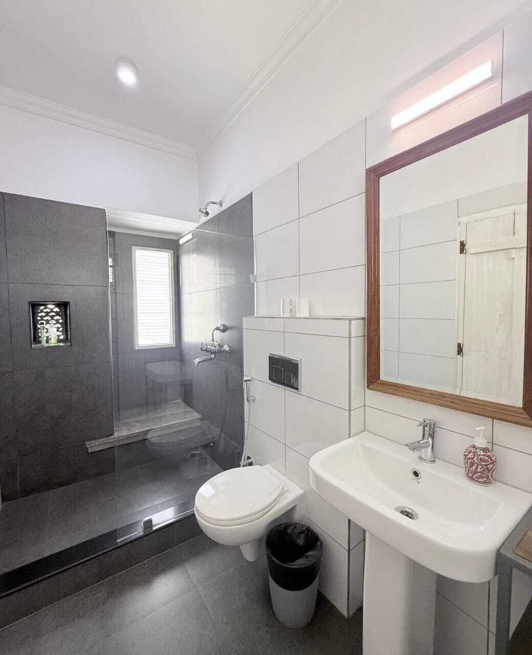 Een moderne badkamer met een douchecabine van glas, een toilet en een wastafel met spiegel.