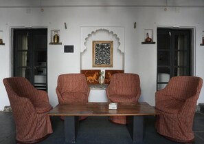 A room with a wooden table and four striped chairs. There is a decorative wall piece above the table. - Little Garden Guest House (Udaipur)