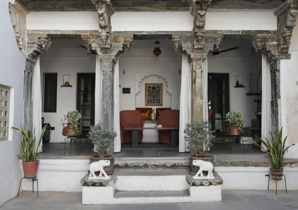 A traditional building with a porch, stone columns, and potted plants.