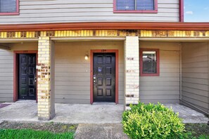 A two-story house with a front porch, two doors, and a small window. - Regency Place | Modern Comfort, 2BR Home (Beaumont)
