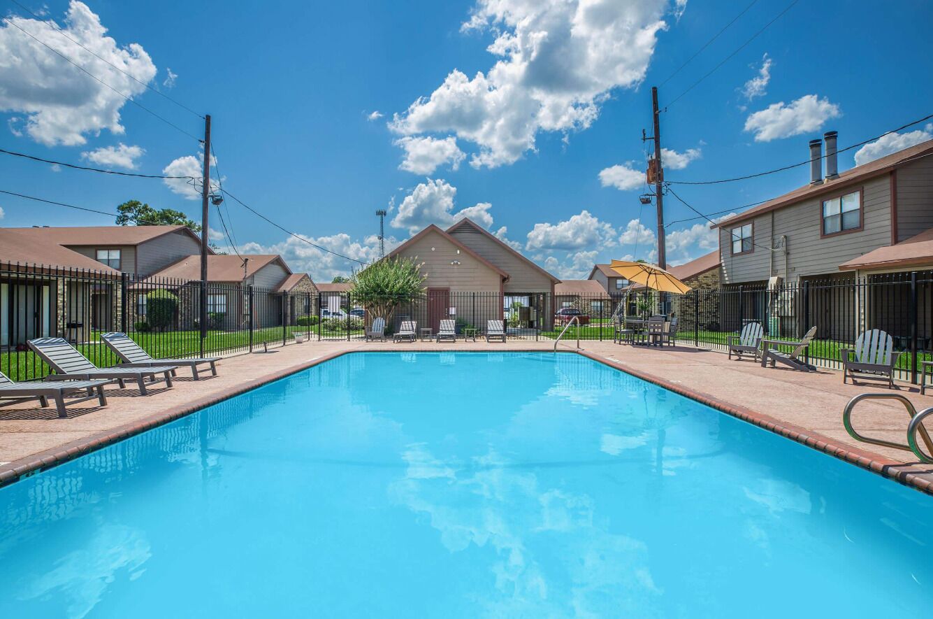 Ein Pool mit Liegestühlen und einer überdachten Liegefläche, umgeben von Häusern.