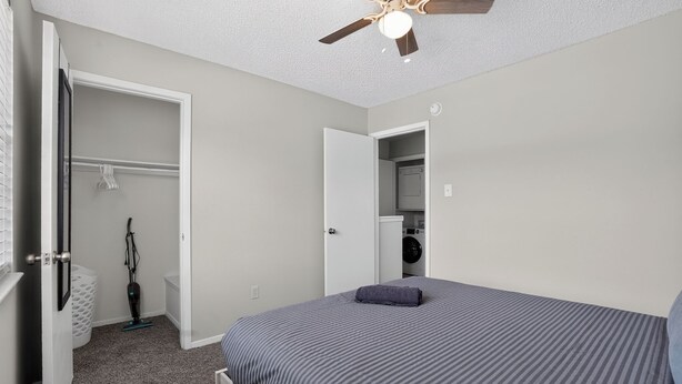 Ein Schlafzimmer mit Bett, Deckenventilator, Kleiderschrank und Waschbereich.