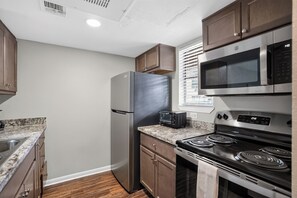 Eine kleine Küche mit Kühlschrank, Mikrowelle, Herd und Backofen.