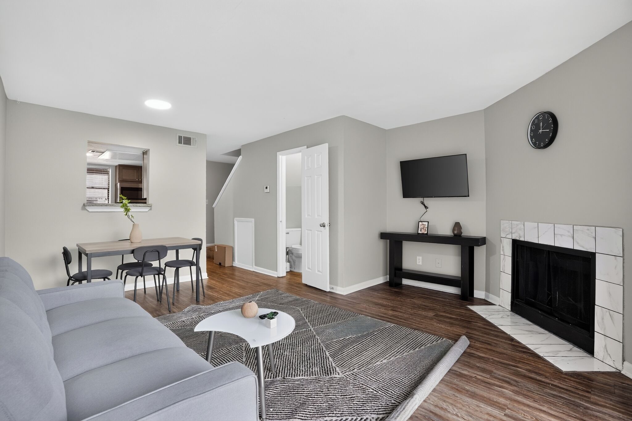 Un salon moderne avec un canapé gris, une table basse et une cheminée.