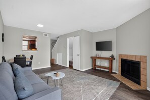 A modern living room with a gray sofa, a coffee table, and a fireplace. - Regency Place | Cozy 2BR for Work & Rest (Beaumont)
