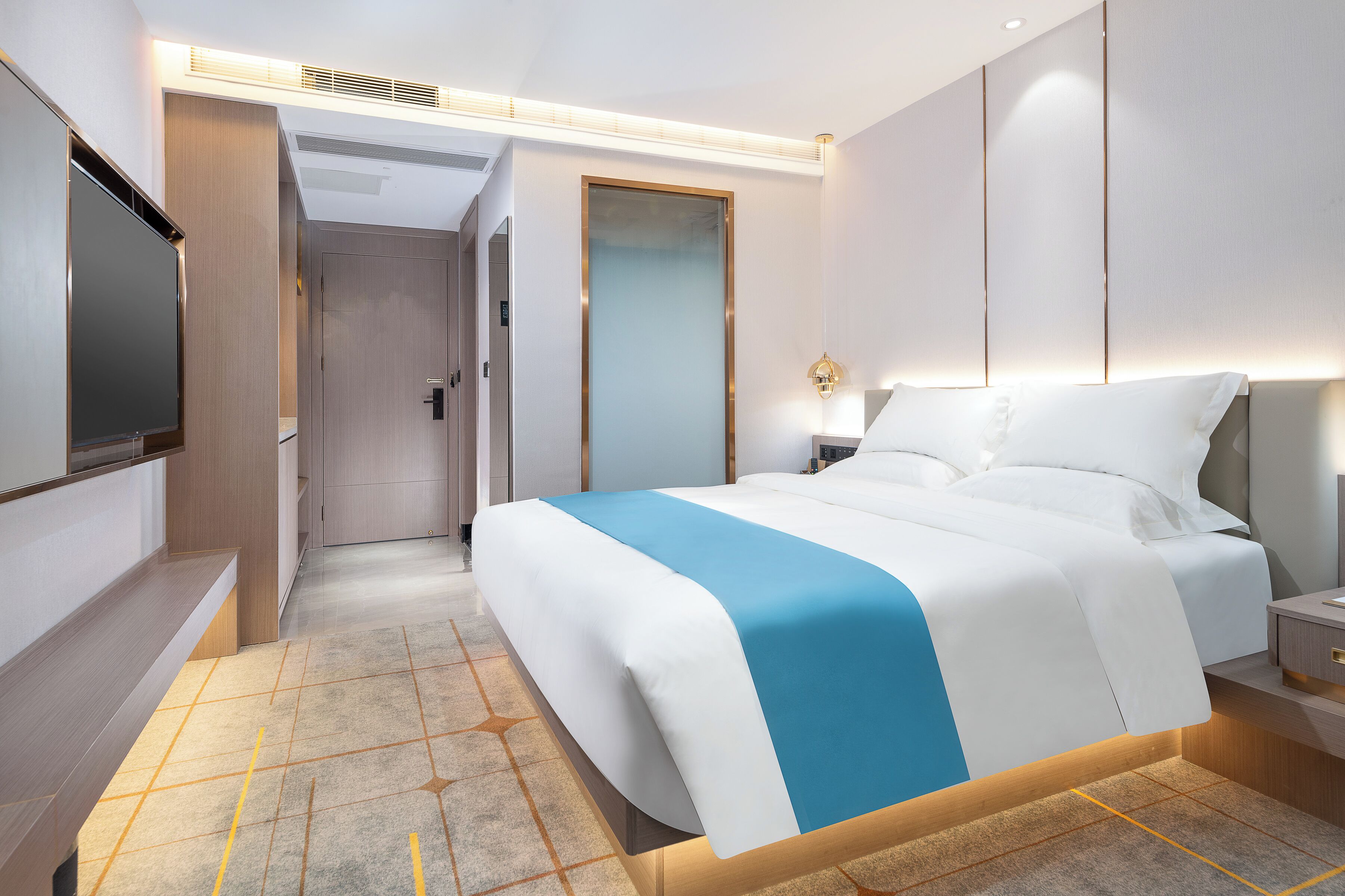 Una habitación de hotel moderna con una cama grande, mesitas de noche, un televisor de pantalla plana y un vestidor.