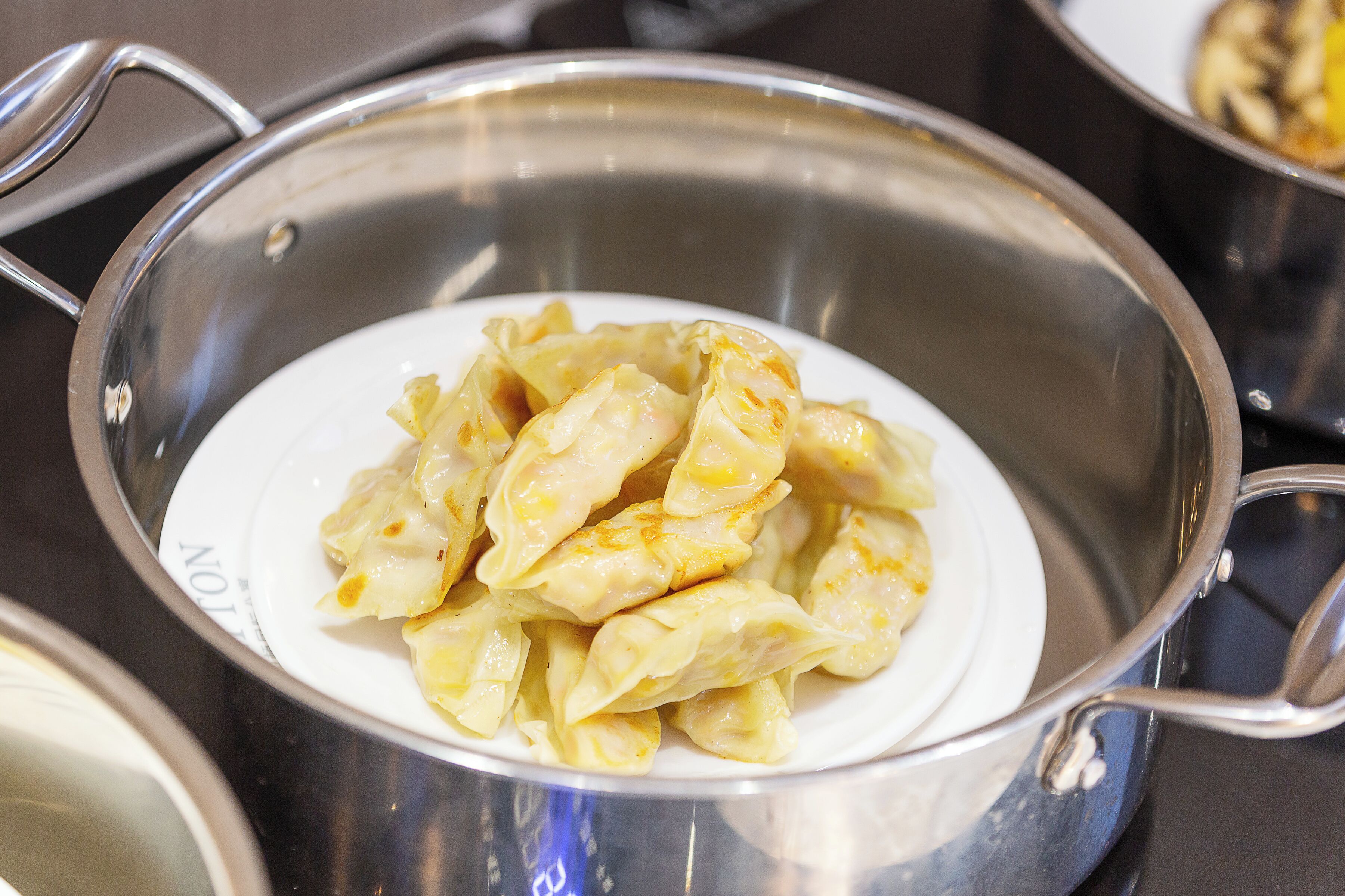 A stainless steel pot with a white interior containing dumplings.