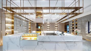 Un interior moderno con una barra central, suelo de mármol y una vitrina de cristal.