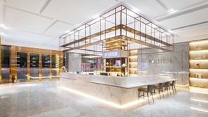 Een moderne hotelentree met een centraal gelegen bar, marmeren vloeren en een glazen scheiding.