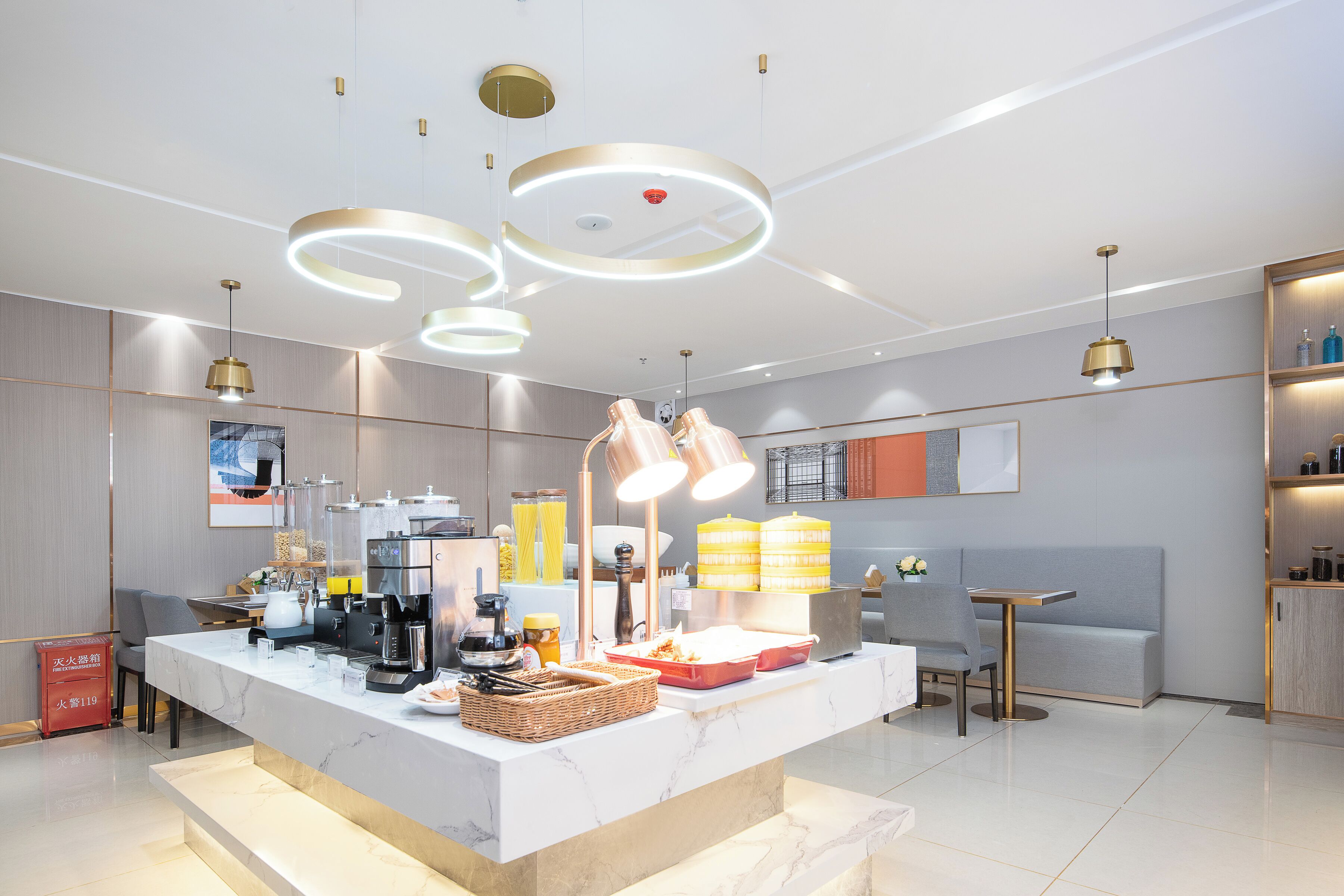 Eine moderne Bar mit Marmorplatte, Kaffeeautomaten und einer Sitzecke mit Sofa und einem kleinen Tisch.