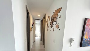 A hallway with a tiled floor, a map artwork on the wall, and a chair on the right. - Exclusive 3 Bedroom Apartment - Sunset 47 (Cartagena)