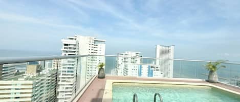 Piscina en la azotea con vistas despejadas a edificios altos y al océano.