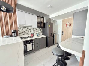 A modern kitchen with a central island, a built-in oven, a refrigerator, and a coffee maker. - Exclusive 3 Bedroom Apartment - Sunset 47 (Cartagena)