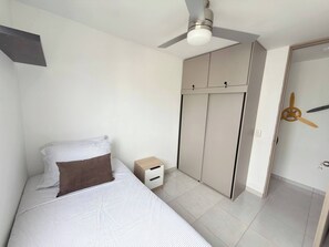 A bedroom with a bed, a nightstand, a wardrobe, and a ceiling fan. - Exclusive 3 Bedroom Apartment - Sunset 47 (Cartagena)