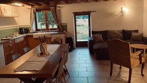 A cozy interior with a dining area, kitchen, and seating space. - Gîte des Charbonneaux (Avrée)