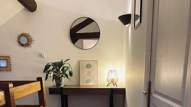 A hallway with a wooden bench, a rug, a desk with a lamp, a mirror, and a door. - Gîte des Charbonneaux (Avrée)