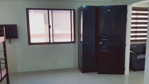 A room with a sliding door, a flat-screen TV mounted on the wall, and a window with blinds. - Avana Hills Boracay Prime - Grand (Boracay Island)