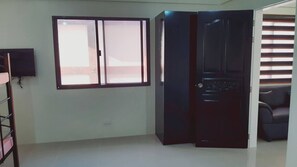 Una habitación con una puerta corredera, un televisor de pantalla plana montado en la pared y una ventana con persianas.