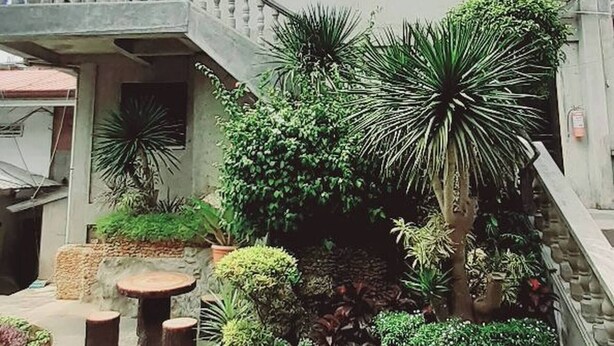 A two-story building with a balcony, a staircase leading to the upper floor, and a well-maintained garden with various plants and shrubs. - Avana Hills Boracay Prime - Grand (Boracay Island)