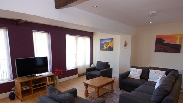 A living room with a flat-screen TV, two sofas, a coffee table, and a bookshelf. - Old Lyn Cottage (Lynmouth)