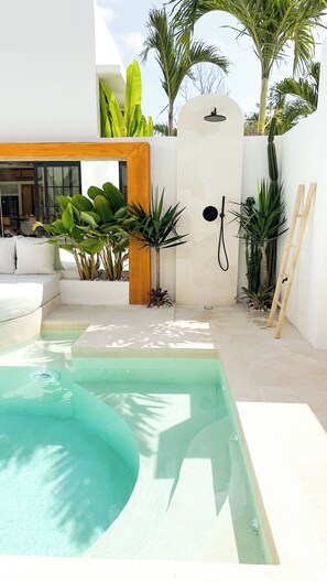 A modern outdoor pool area with a white wall, a wooden door, and various plants. - Designer 2BR Private Pool Villa Near Nyang Nyang Beach Uluwatu (kuta selatan)