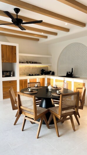 Una cucina moderna con isola centrale, mobili in legno e un'area pranzo con tavolo e sedie rotonde.