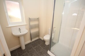 A bathroom with a white sink, toilet, and glass shower enclosure. - LT Properties Serviced Apartments (Luton)