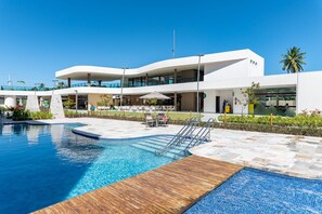 Un hotel moderno con piscina, mobiliario exterior y zona de patio cubierta.