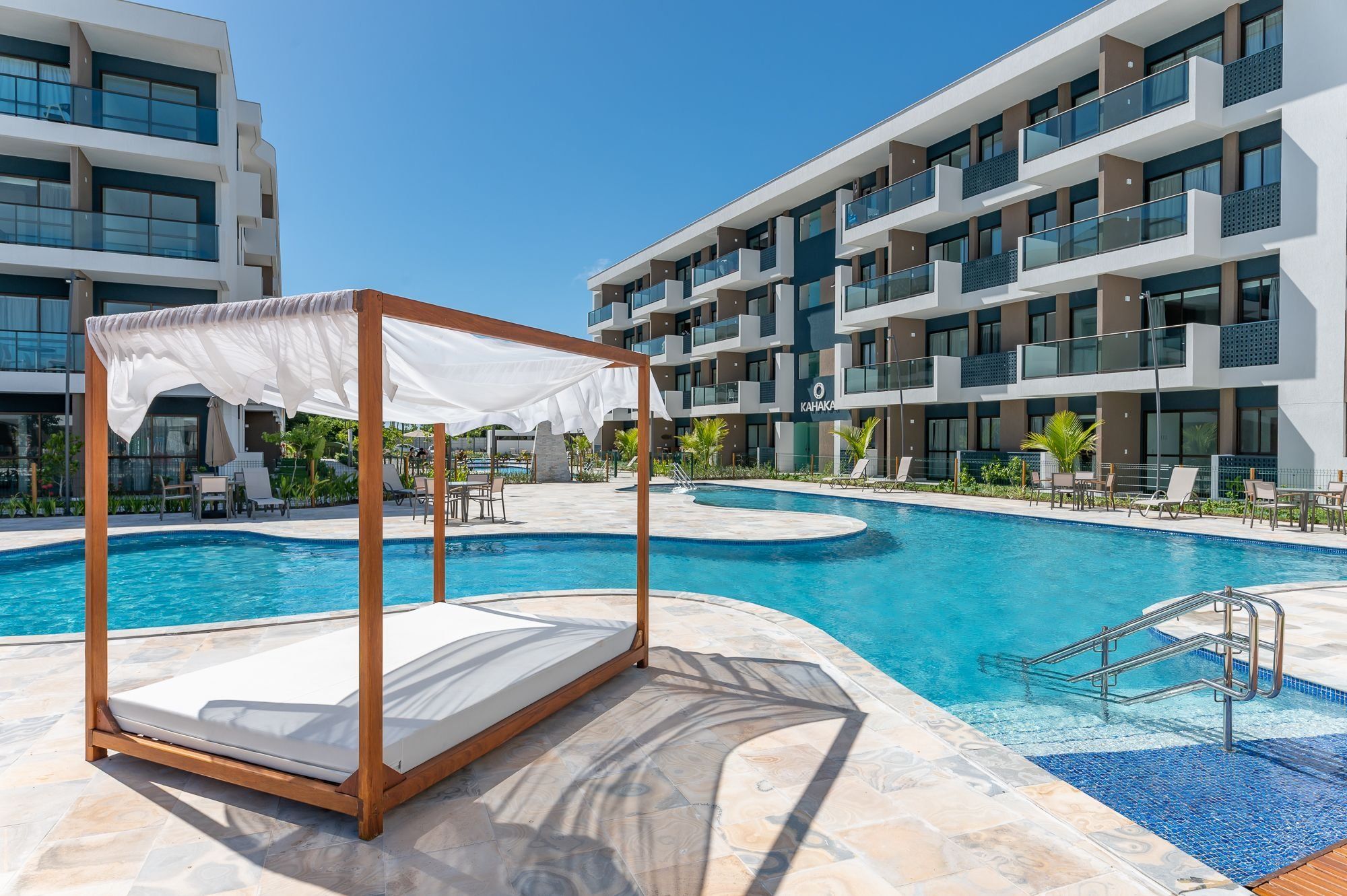 Un hotel moderno con piscina, mobiliario exterior y una zona de relax cubierta.