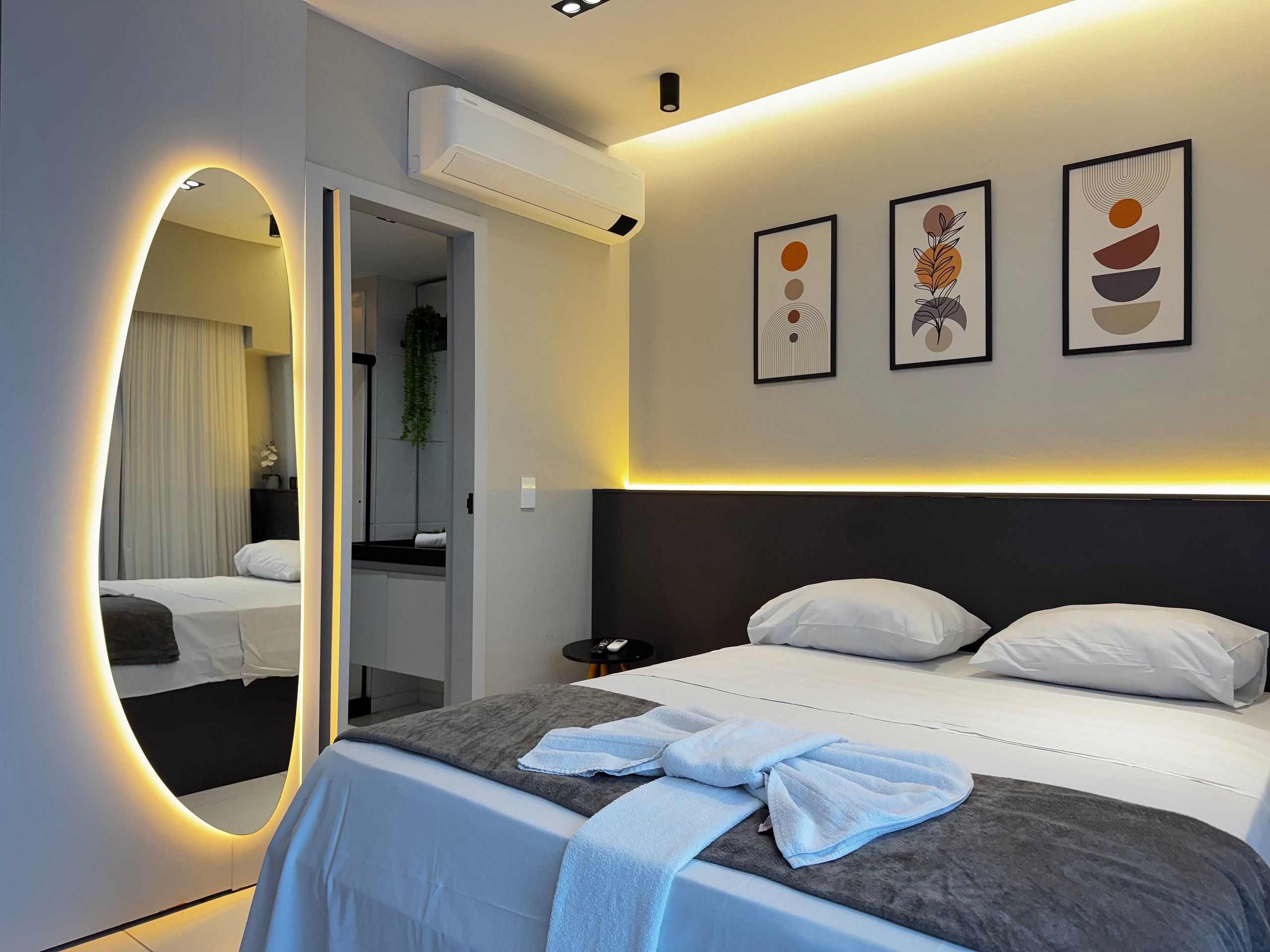 Ein modernes Hotelzimmer mit einem großen Bett, einem Nachttisch, einem Spiegel und Wandbildern.