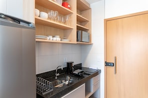 A modern kitchen with a built-in oven, a coffee maker, and a microwave on the countertop. - Makia Beach Experience Muro Alto (Ipojuca)